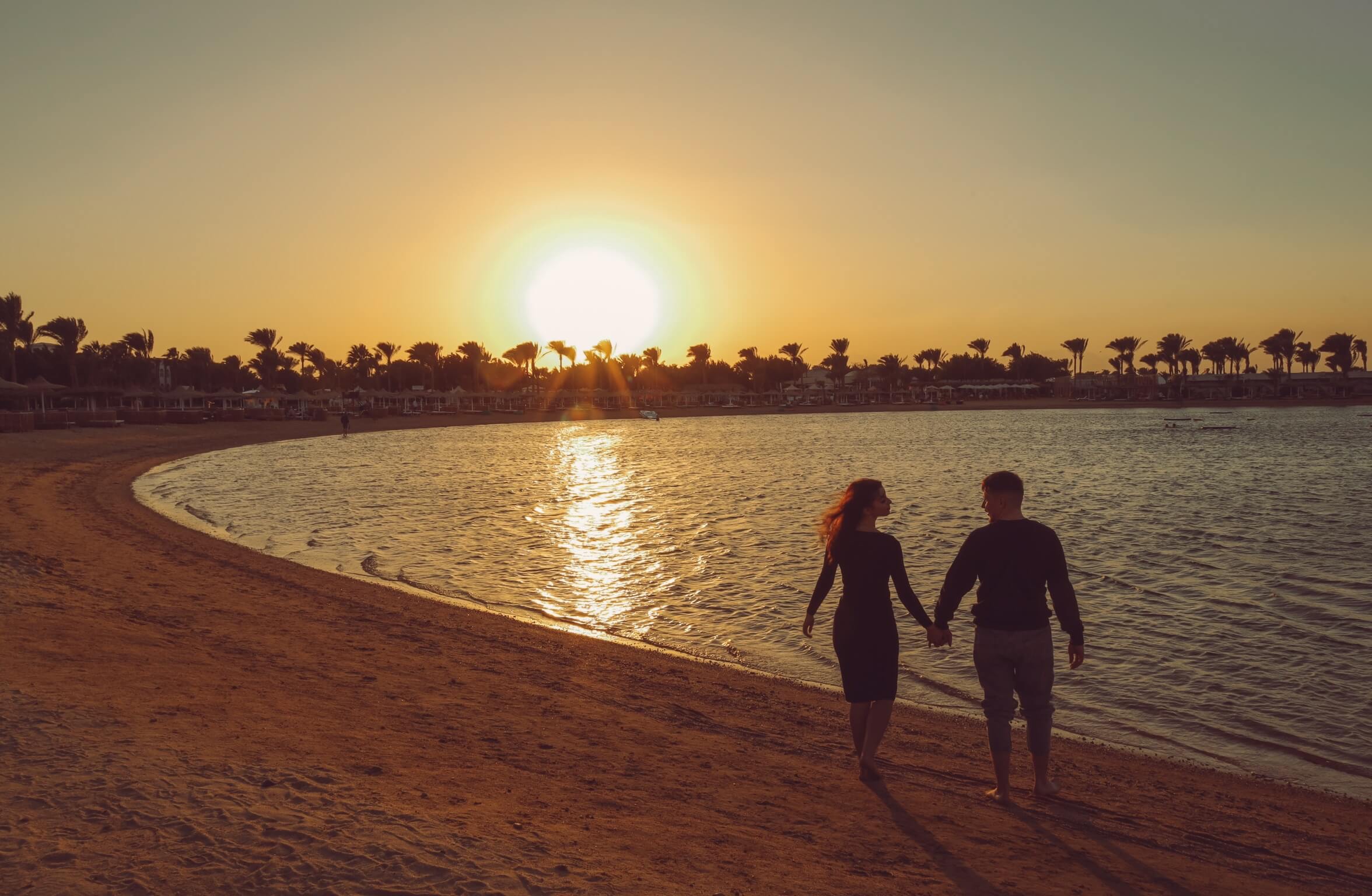 Red Sea Romance - A couple stands close together on a tranquil Hurghada beach at twilight.
